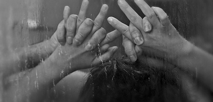 couple with hands pinned in against foggy shower window