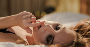 woman in bed with eyes closed with finger in her mouth